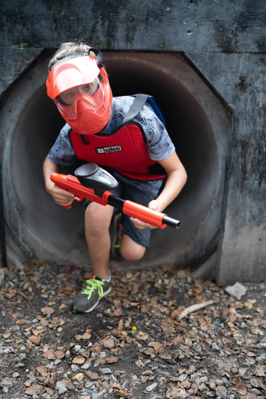 enfant jouant au paintball et sortant d'un tunnel
