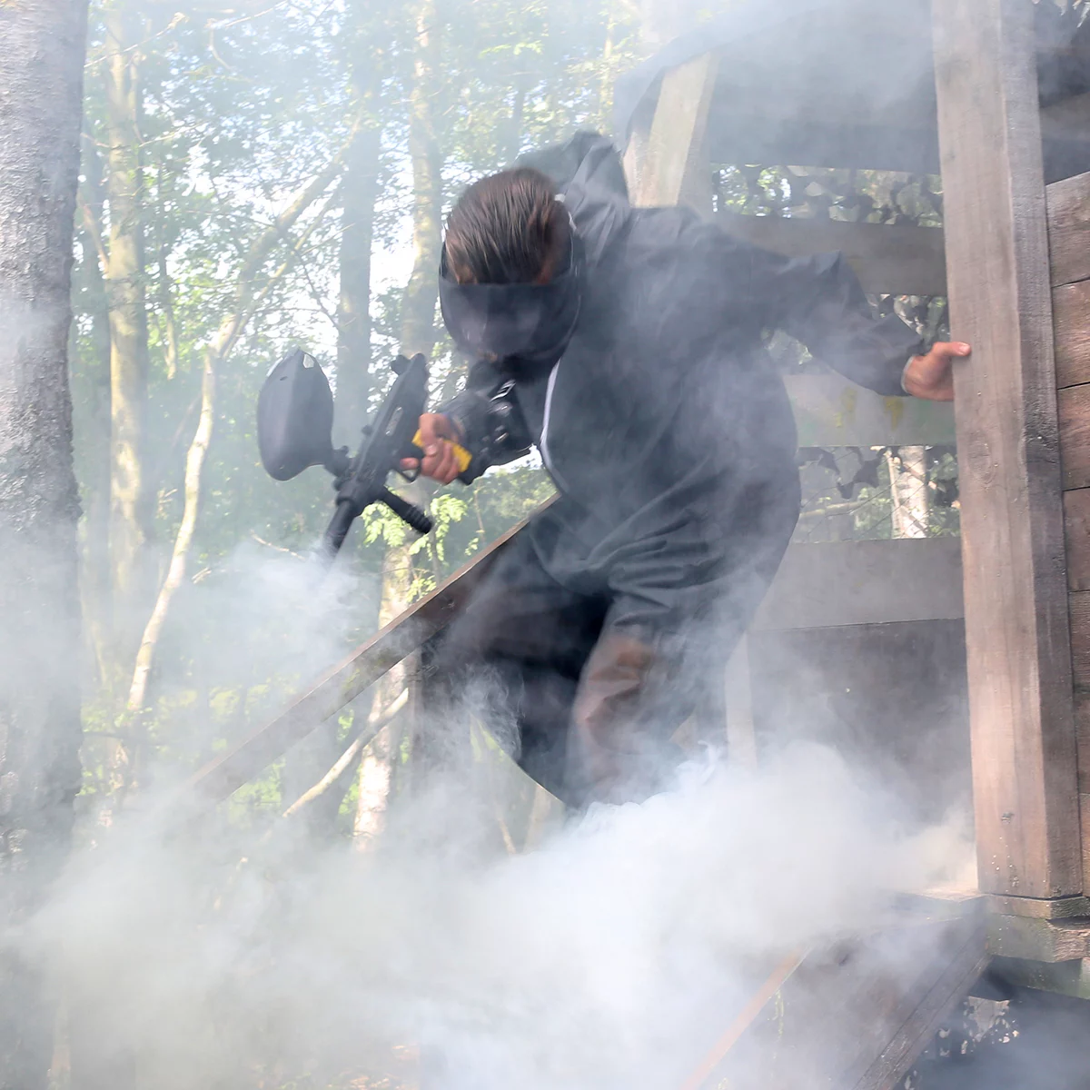 joueur de paintball sortant d'un mirador avec de la fumée.